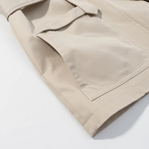 Detail of beige jacket showing a large utility pocket and fine stitching on fabric