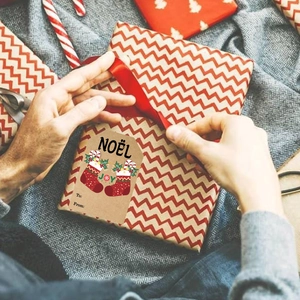 Kraft paper Christmas gift tags featuring festive red stocking patterns on cozy home background