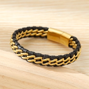 Detail of black braided leather bracelet with gold chain and magnetic metal clasp