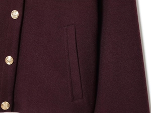 Detail der burgunderroten Wolljacke mit strukturiertem Stoff und goldenen geprägten Knöpfen