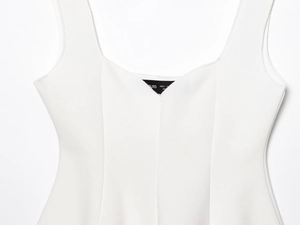 Dettaglio del top bianco senza maniche con trama a maglia ed etichetta della taglia S