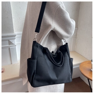 Detail of adjustable shoulder strap and metal hook on minimalist black canvas tote bag