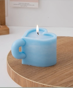 Light blue heart-shaped cup candle lit on a circular wooden tray for home decor