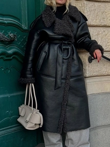 Detail of long shearling leather coat featuring plush lapels and a waist belt fastening