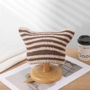 Macro detail of brown and beige striped knit cat ear hat on wooden stand