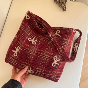 Détail du sac à carreaux rouge et noir avec motifs de nœuds brodés en cordelette