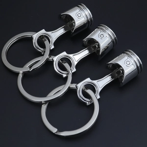 Detailed close-up of three metallic piston-shaped keychains on a sleek black background