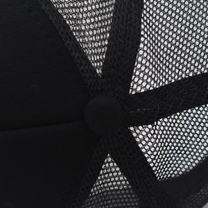Macro shot of black mesh trucker hat top with button and six-panel stitching details