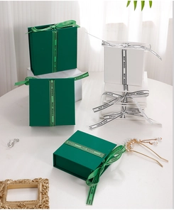 Detail view of emerald green and white jewelry flip boxes with silk Best Wishes ribbons