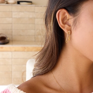 Gros plan de boucles d'oreilles trombone dorées avec strass et motif Love