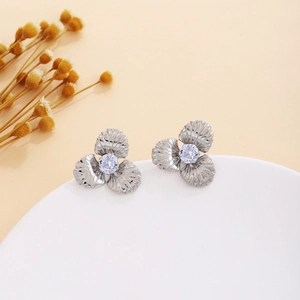 Detailed macro view of silver flower earrings with textured petals and zircon centers