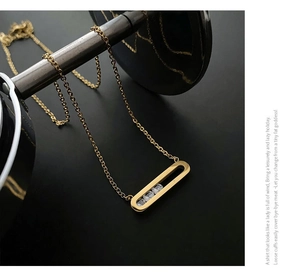 Detailed view of an 18K gold plated necklace with three-stone oval pendant on black background