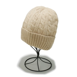 Detailed close-up of beige cable knit beanie showing thick texture and ribbed cuff