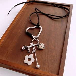 Close-up of heart-shaped clasp and horse pendant on vintage cotton cord necklace