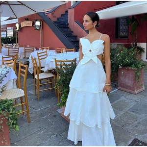 Détail d'une robe longue blanche à taille haute avec découpe florale et jupe à volants