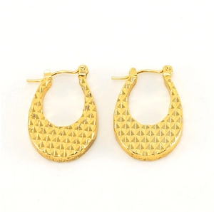 Detail view of 18K gold earrings with textured pyramid pattern and polished finish