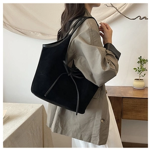Detail of black matte tote bag with side bow tie design shown on model shoulder