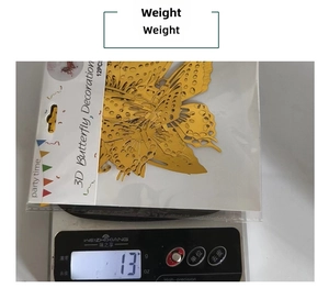 Detail showing weight of 12pcs gold 3D hollow butterfly wall stickers on a scale