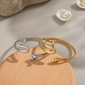 Vue détaillée des bracelets en forme de serpent or et argent sur un support en bois