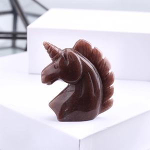 Macro detail of hand-carved dark brown crystal unicorn head sculpture on white pedestal