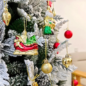 Gros plan d'un traîneau rouge et d'ornements du Père Noël suspendus au sapin de Noël enneigé