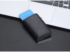 Macro shot of black RFID leather pop-up wallet showing multiple blue card slots on laptop