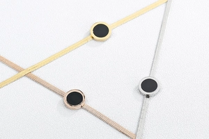 Macro detail of gold, silver, and rose gold flat snake chains with black shell pendants