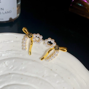 Detailed close-up of vintage pearl bow earrings with a black rose motif on ceramic