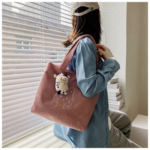 Pink corduroy tote bag detail with rabbit embroidery and a cute cow doll charm