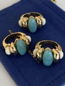 Detailed view of three vintage gold rings with light blue stones on a blue fabric bag
