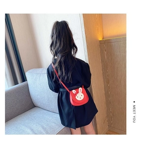 Rear view of a young girl wearing a cute red bunny crossbody bag with white flap