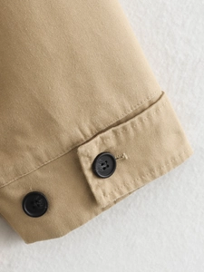 Detail of khaki jacket cuff featuring twill fabric texture and black resin buttons