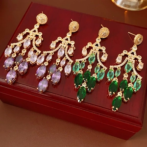 Close-up of luxury gradient zircon teardrop earrings in purple and green on a wooden box