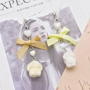 Cute yellow plush bunny and bear phone charms with ribbons and beads on magazine background