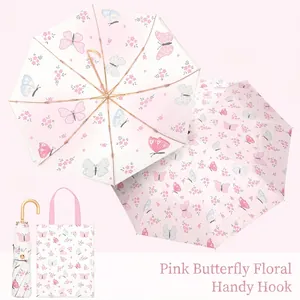 Detail of pink butterfly floral folding umbrella with double-sided print and gold hook handle