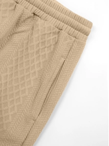 Detail of beige jacquard knit pants with elastic waistband and side pocket design