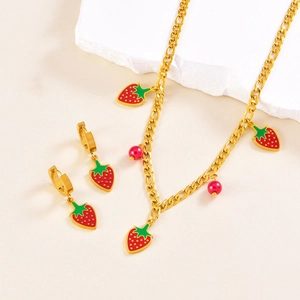 Detailed shot of golden necklace and strawberry earrings on white stone props