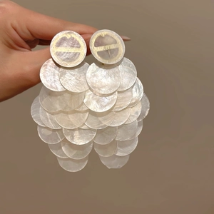 Detailed view of white shell petal earrings with elegant gold accents and silver needle