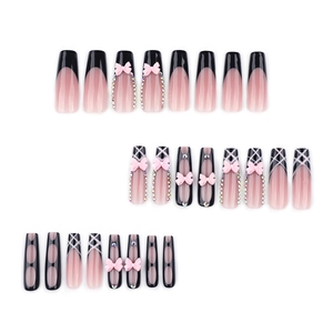 Extra long coffin press-on nails in black and nude with pink bows and rhinestones