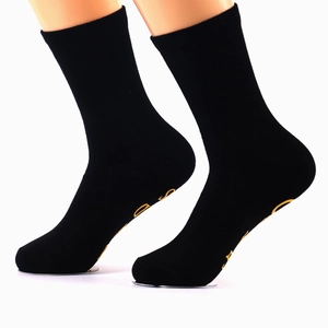 Mid-calf black cotton crew socks with anti-slip grip sole worn by a model in studio