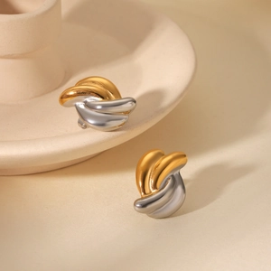 Detailed close-up of two-tone twisted wave stud earrings in gold and silver steel finish