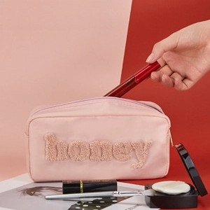 Detailed macro view of pink nylon glasses case with honey embroidery and gold zipper