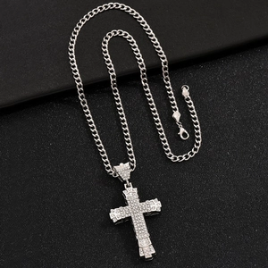 Macro shot of silver hip-hop Cuban chain necklace with iced-out cross pendant on black surface