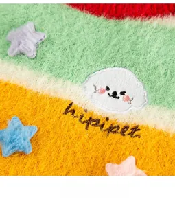 Close-up of colorful striped dog sweater with plush star detail and brand embroidery