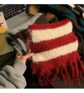 Close-up of soft red and white striped knit scarf with decorative tassels and plush texture