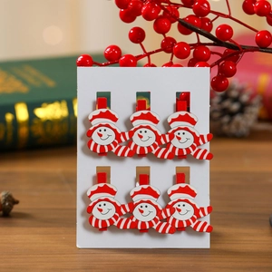 Detail of six wooden snowman clips on white card with festive background decoration