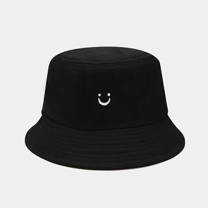 Close-up of a black bucket hat showing a white smile face embroidery on cotton canvas fabric