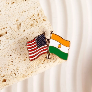 Detailed view of crossed USA and Niger flags enamel brooch on a textured stone surface