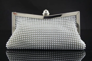 Makroaufnahme der silbernen geflochtenen Pailletten-Clutch mit Kristallknopf und Metallrahmen