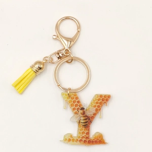 Detail of bee letter Y keychain with yellow tassel and honeycomb acrylic pendant